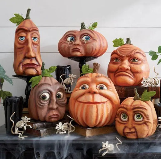 Set of decorative pumpkins with carved faces on a Halloween-themed table.